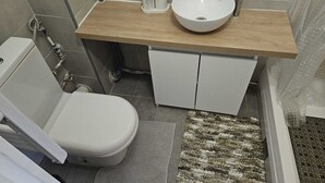 A bathroom with a white toilet, a sink with a wooden countertop, and a shower area. - Studio in Champigny sur marne near Disneyland (Champigny-sur-Marne)