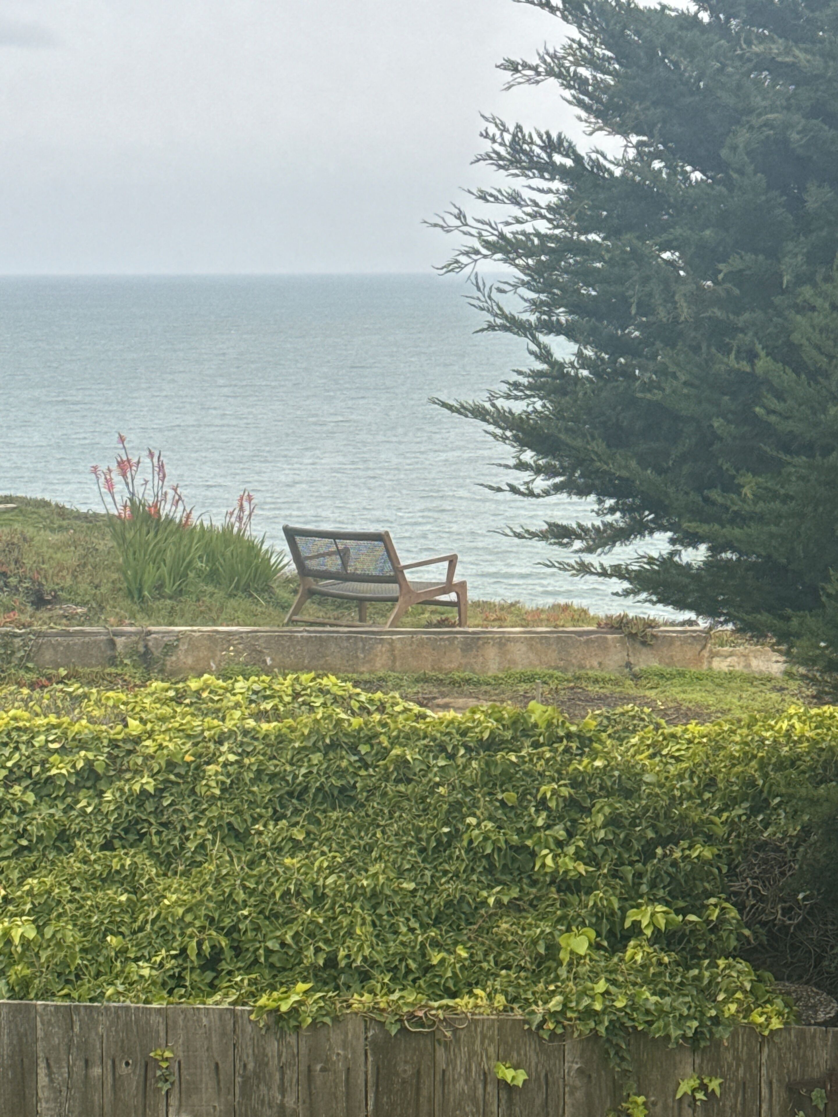 A wooden fence, a chair, and a view of the sea.