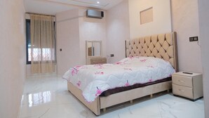 A bedroom with a bed, bedside table, nightstand, and a mirror. - Gulf Serenity Suites (Fès)