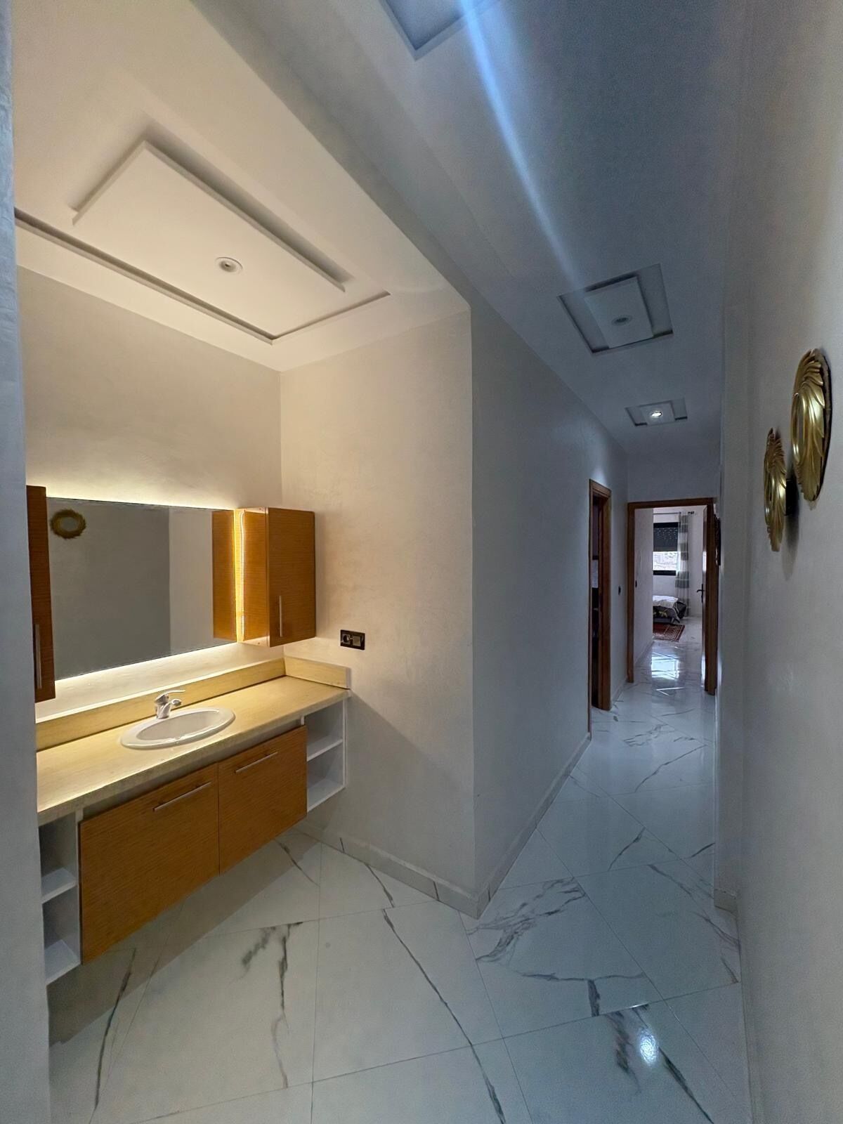 Un baño moderno con un espejo grande, un lavabo y armarios de madera.