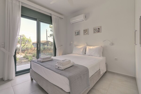 Une chambre à coucher avec un lit, une fenêtre avec des rideaux, un appareil de climatisation et une vue sur l’extérieur.