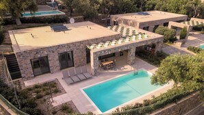 Un edifici modern amb piscina, façana de pedra i zona d'estar a l'aire lliure.