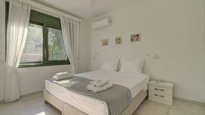 Un dormitori amb un llit, una nitzeta i una finestra amb cortines.