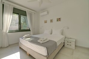 A bedroom with a bed, nightstand, and window with curtains. - Ouzo Stone House2 with Private Pool and Parking (Plomari)