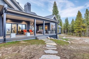 Een modern huis met een overdekte veranda, een pad van stenen en uitzicht op de omliggende bomen.