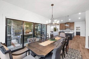 Een moderne keuken met een centraal eiland, een eethoek met een houten tafel en stoelen, en een stenen openhaard.