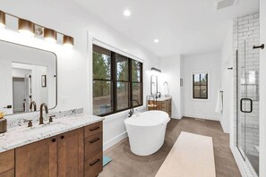 Een moderne badkamer met een groot bad, een dubbele wastafel met een grote spiegel en een ruime douche.