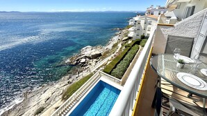 A balcony with a glass table, a clear view of the sea, and a swimming pool. - Beautiful apartment with pool, parking, and views of the Bay of Roses (Roses)