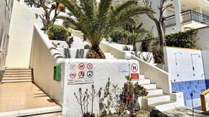 A staircase leading to a building with a sign indicating swimming pool hours. - Beautiful apartment with pool, parking, and views of the Bay of Roses (Roses)