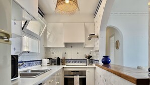 A modern kitchen with white cabinets, a sink, a stove, and a blue vase on the counter. - Apartment in Roses with terrace, private parking, and equipped kitchen (Roses)