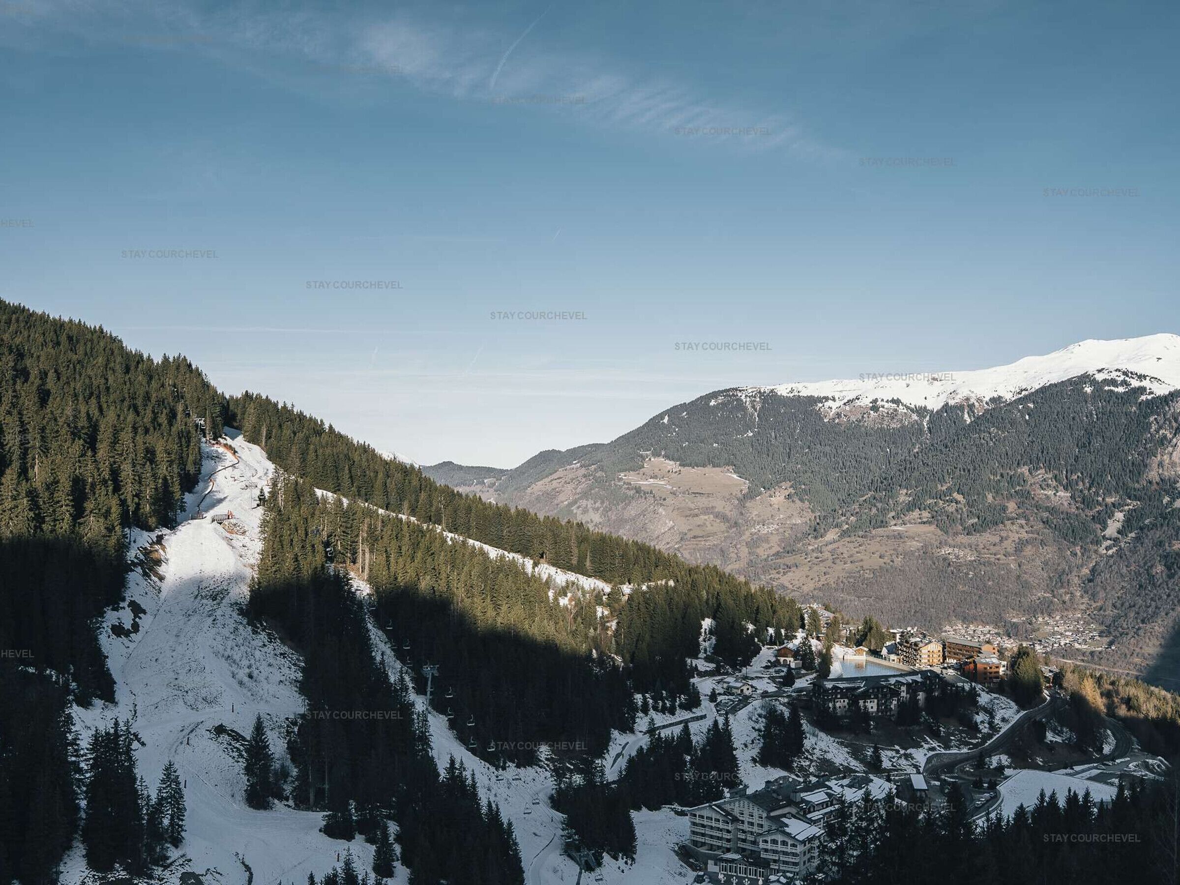 Een bergachtig landschap met een skigebied, inclusief sneeuwbedekte hellingen en gebouwen.