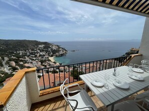 A balcony with a table set for dining, overlooking a coastal town and the sea. - Comfortable apartment in Roses, 2 bedrooms, air conditioning, internet, parking (Roses)
