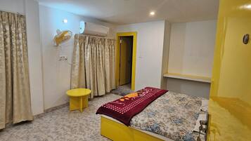 A bedroom with a bed, curtains, an air conditioning unit, and a small table.