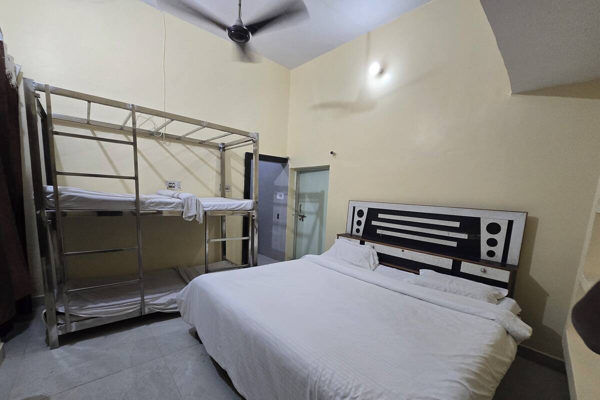 A single-bed room with a bunk bed to the left, a ceiling fan, and a door to the right.