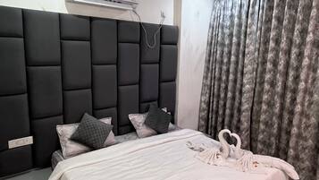 Une chambre moderne avec un grand lit, une tête de lit rembourrée, un appareil de climatisation et un rideau.