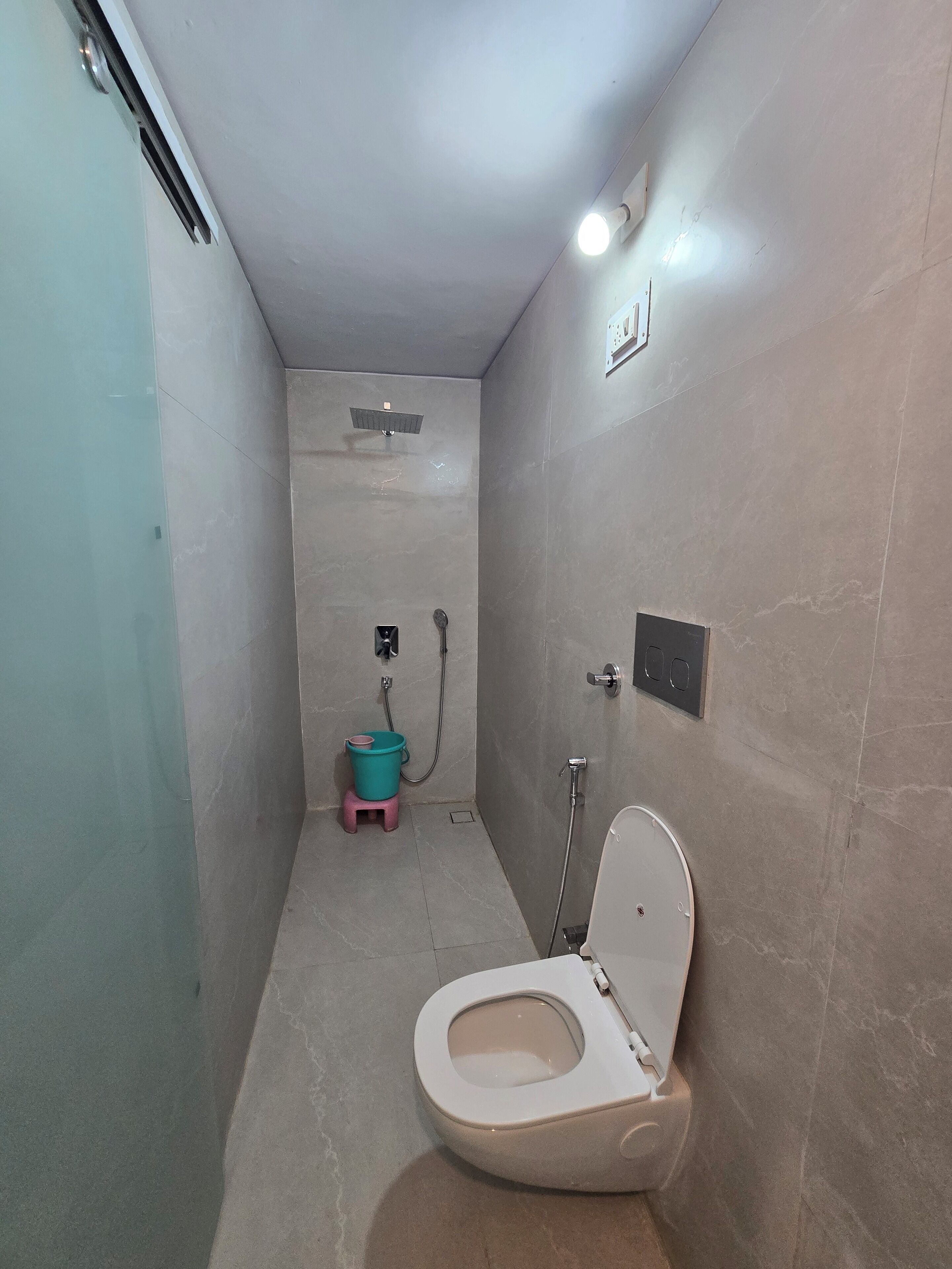 A small, narrow bathroom with a toilet, a shower, and a sink.