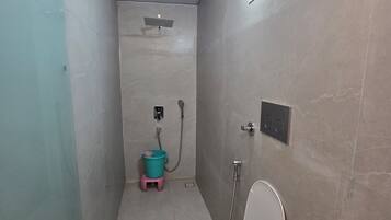 A small, narrow bathroom with a toilet, a shower, and a sink.