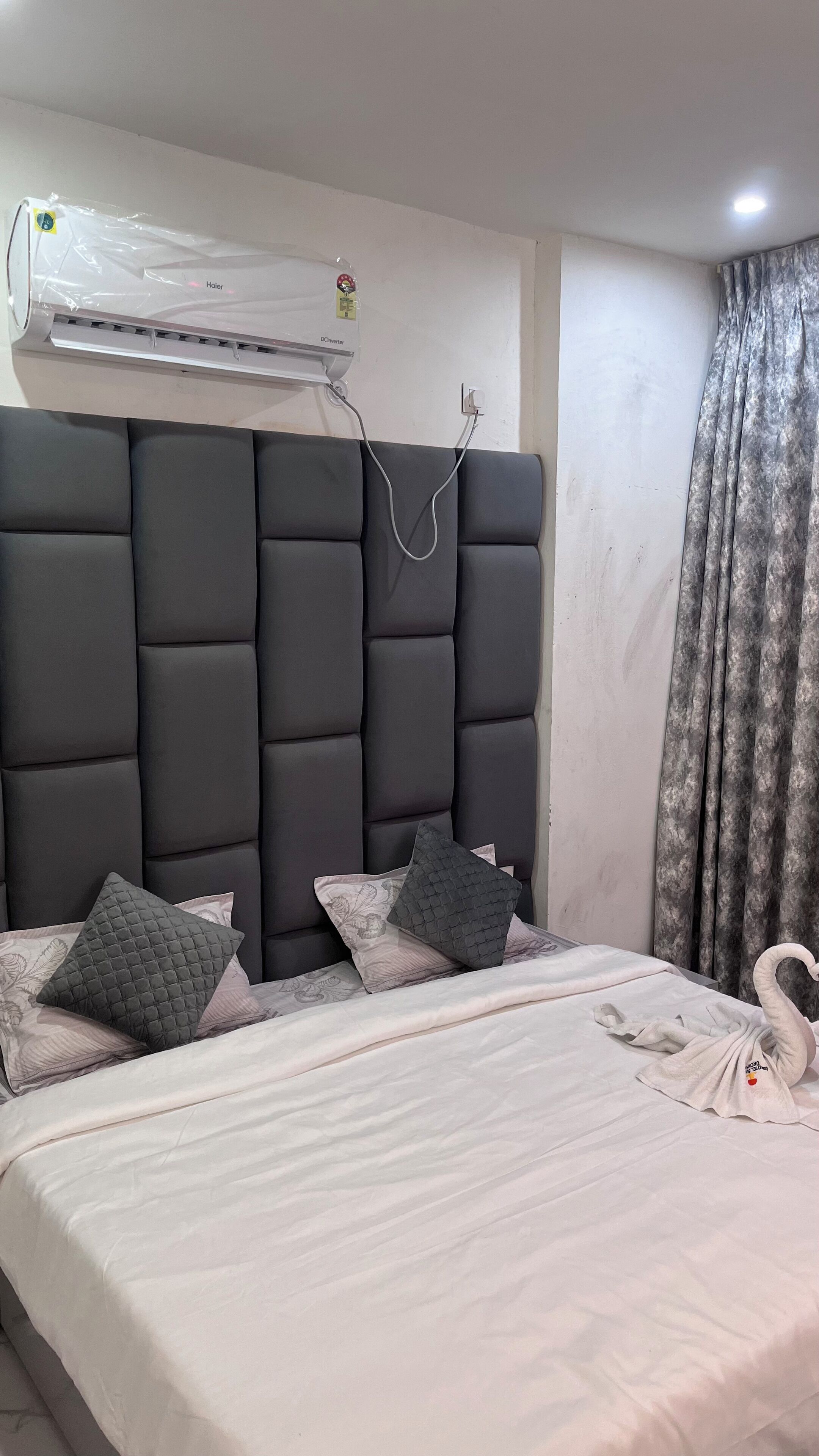 Un dormitorio con una cama grande, un cabecero oscuro y un aire acondicionado instalado en la pared.