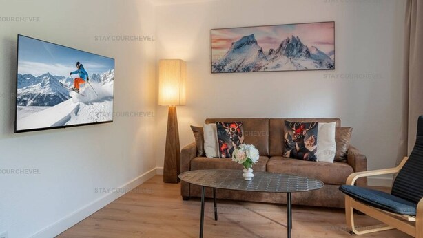 A living room with a flat-screen TV, a sofa with decorative pillows, a coffee table, and a lamp.