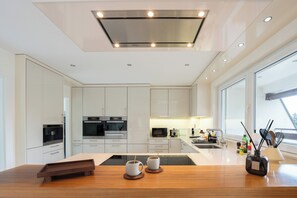 Une cuisine moderne avec des meubles blancs, un îlot central et une grande fenêtre offrant une vue dégagée.