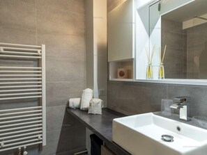 Ein modernes Badezimmer mit einem weißen Waschbecken, einem Handtuchhalter und einem Spiegel.