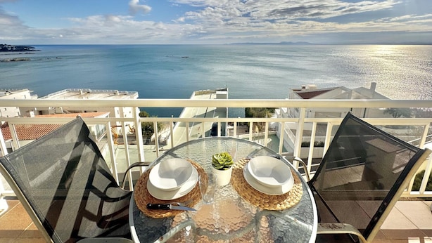 A balcony with a table set for two, overlooking a coastal view. - Beautiful apartment with pool, WiFi and parking, 10 min from the beach (Roses)