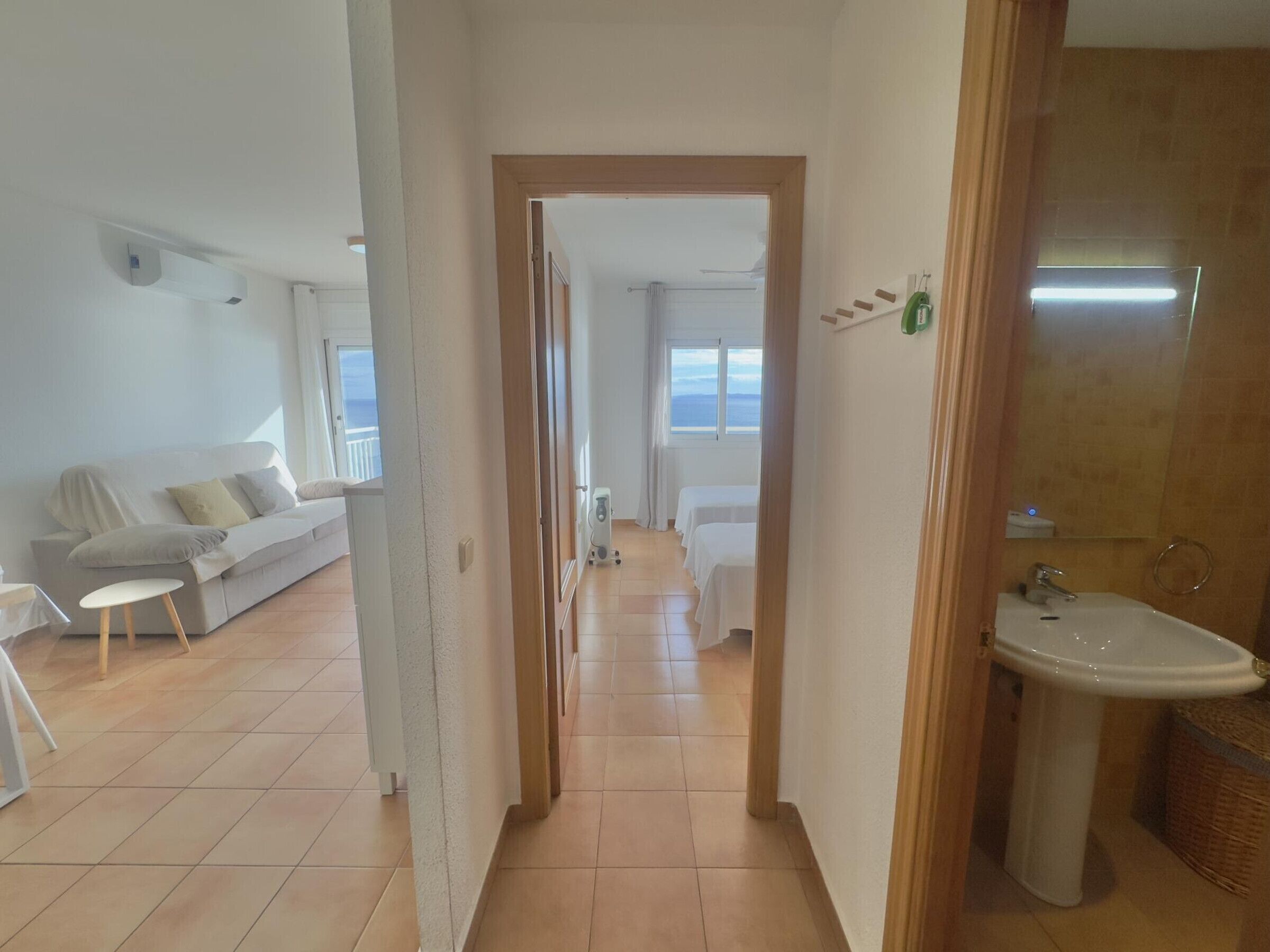 Camera d'albergo con divano, un tavolino, un letto e bagno con lavandino e specchio.