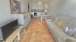 A compact living space with a kitchenette, a dining area, and a sofa. - Beautiful apartment with pool, WiFi and parking, 10 min from the beach (Roses)