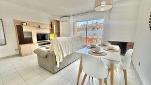 Una sala moderna con sofá, televisor y mesa de comedor preparada para cuatro.
