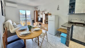 A compact living space with a dining area, kitchenette, and a balcony with a view. - Charming Apartment in Central Roses, 400m from Beach with Private Parking and Wi-Fi (Roses)