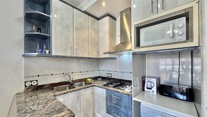 A modern kitchen with granite countertops, stainless steel appliances, and a built-in microwave. - Charming Apartment in Central Roses, 400m from Beach with Private Parking and Wi-Fi (Roses)