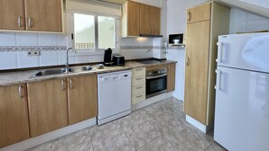 Una cocina moderna con armarios de madera, lavavajillas integrado, microondas y refrigerador.