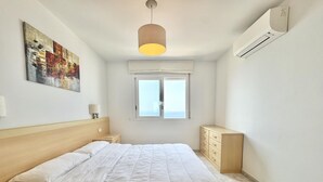 Un dormitorio con cama, mesitas de noche, cómoda, ventana y lámpara de techo.