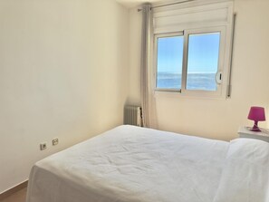 Ein Zimmer mit Bett, Fenster mit Ausblick, Heizkörper und Lampe.
