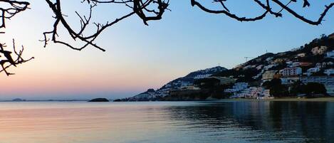 A coastal town with buildings on a hillside overlooking calm waters.