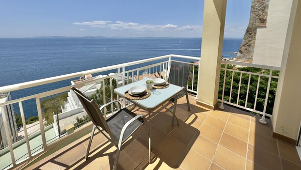 A balcony with a table set for two, overlooking a coastal view. - Beautiful apartment with pool, air conditioning, and parking 700m from Roses beach (Roses)