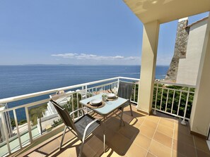 Varanda com mesa posta para dois, com vista para o litoral.