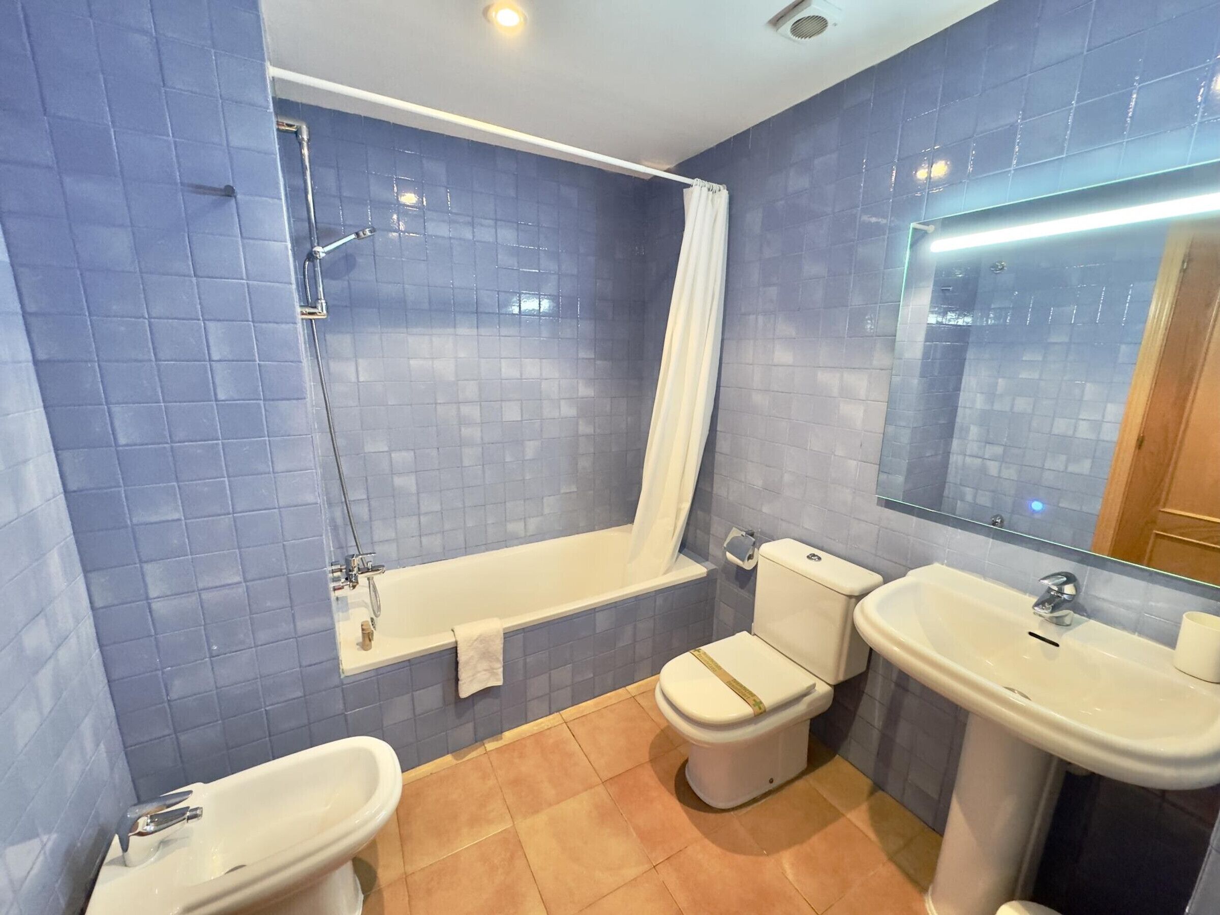 A bathroom with a bathtub, toilet, bidet, and sink.
