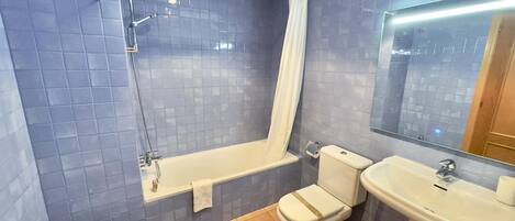 A bathroom with a bathtub, toilet, bidet, and sink.