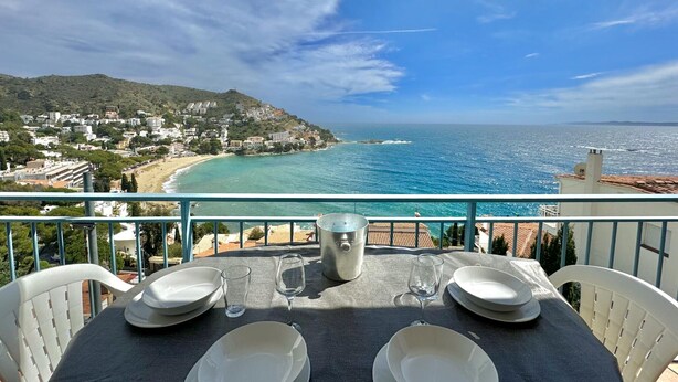 Une table dressée pour deux personnes, avec vue sur une ville côtière et la mer.