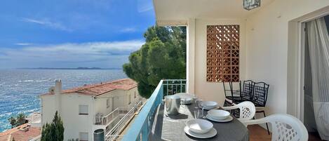Un balcón con una mesa lista para comer, con vista al mar.