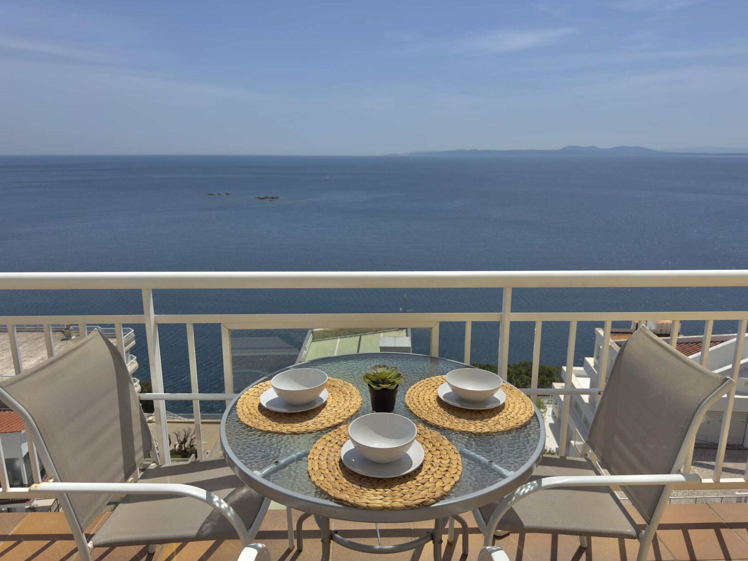 Ein Balkon mit Tisch für zwei Personen mit Blick aufs Meer.