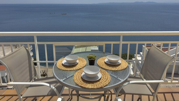 Un balcón con una mesa dispuesta para dos personas, con vista al mar.