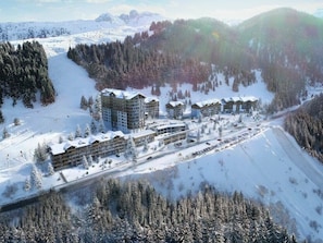 A snow-covered resort with multiple buildings, ski slopes, and a forested area. - Comfortable apartment for 6 in Courchevel, direct ski-in/ski-out (Courchevel 1650)