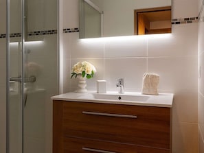 A bathroom with a glass shower enclosure, a white sink with a vase of flowers, a towel, and a mirror above the sink. - Comfortable apartment for 6 in Courchevel, direct ski-in/ski-out (Courchevel 1650)