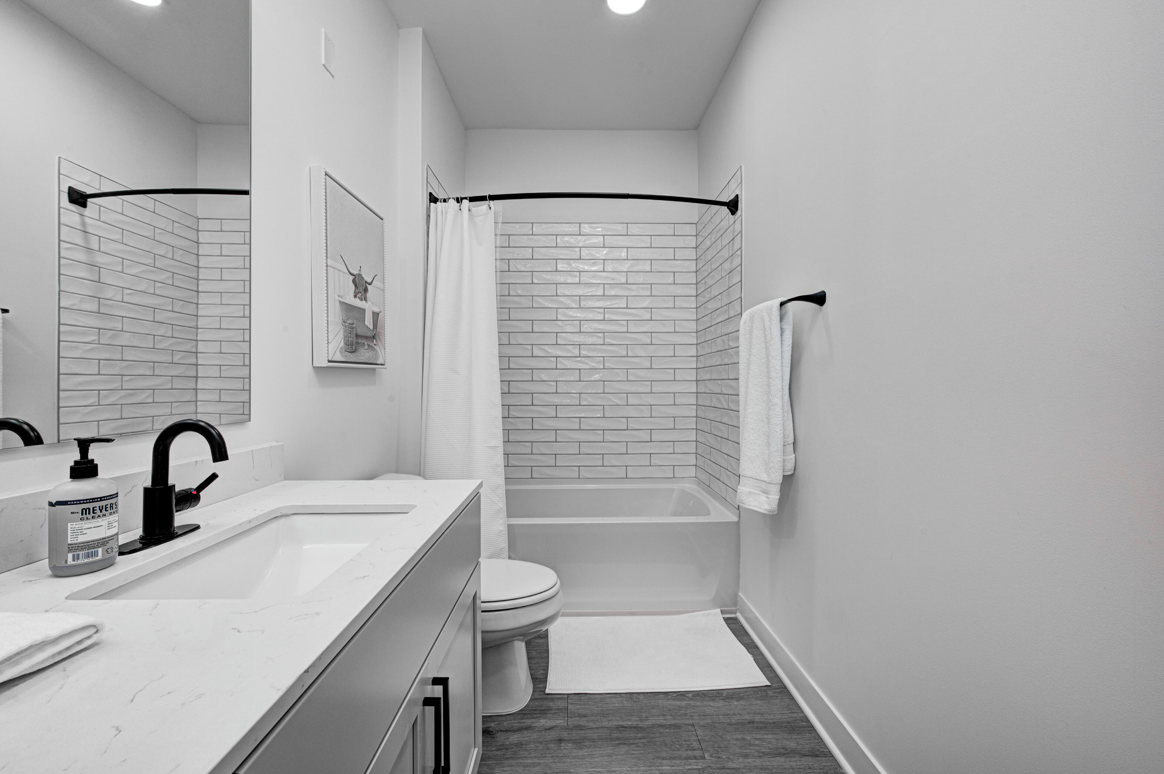A modern bathroom with a white sink, black faucet, and a white toilet.