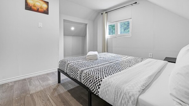 A bedroom with a bed, a window, a door, and a wall-mounted light fixture. - Mid-term stay 3BR Furnished House(monthly rental) (Hamilton)