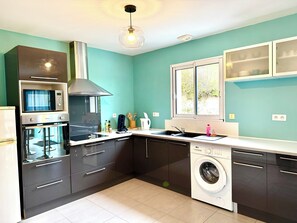 A compact kitchen with a microwave, oven, sink, and washing machine. - Caporizon-Villa Aubepines (Coulounieix-Chamiers)