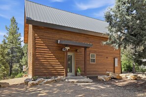 A wooden cabin with a metal roof, a door, and a small window. - Lovely 2-bedroom cabin bordering Zion's national Park, Close to cable Mountain. (Orderville)