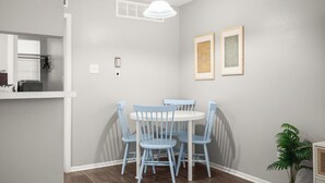 A dining area with a round table and four blue chairs, a white pendant light, and two framed pictures on the wall. - Modern Central Austin Retreat Near UT & Downtown (Austin)